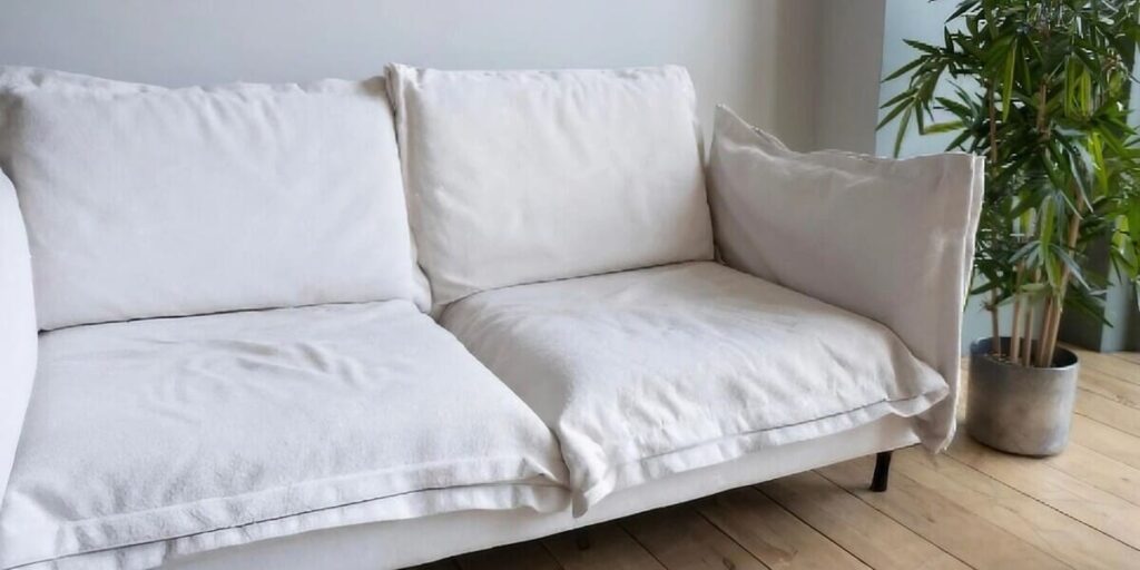 sofá cama blanco con planta al lado