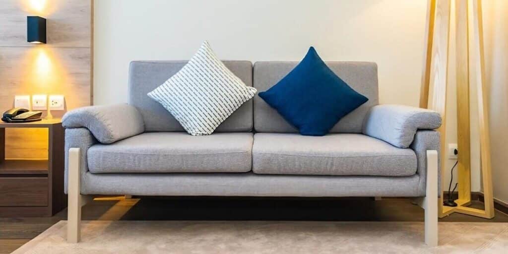 sofá gris dos plazas cojines blanco azul
